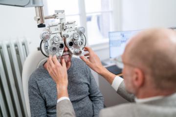 Optometrist adjusting phoropter for senior patient's vision test- Stock Photo or Stock Video of rcfotostock | RC Photo Stock