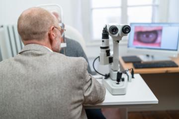 Optometrist looking through Keratograph during an eye examinatio- Stock Photo or Stock Video of rcfotostock | RC Photo Stock