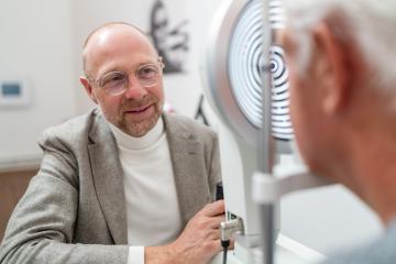 Optometrist smiling at patient during eye exam with Keratograph - Stock Photo or Stock Video of rcfotostock | RC Photo Stock