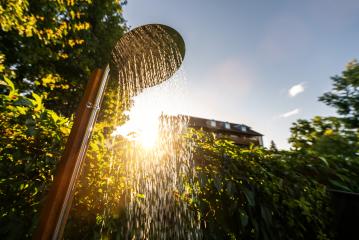 Outdoor shower sprinkler in the garden for swimming in the resort pool at sunrise. Golden Hour Refreshment Spa wellness concept image- Stock Photo or Stock Video of rcfotostock | RC Photo Stock