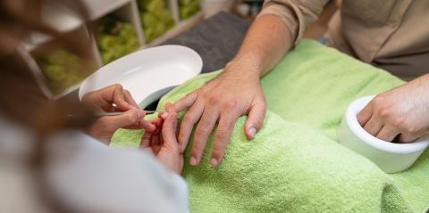Over-the-shoulder shot of a manicure with a client soaking nail bed from his hand in a bowl and the other hand on the other hand a cuticle pusher being used on a fingernails in a beauty salon- Stock Photo or Stock Video of rcfotostock | RC Photo Stock