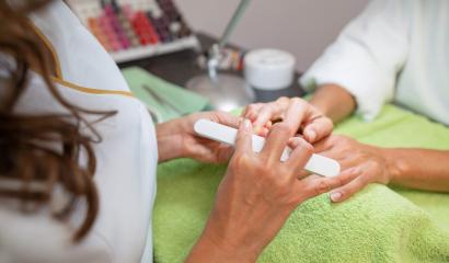 Over-the-shoulder view of a manicurist filing a client's nails in a beauty salon setting- Stock Photo or Stock Video of rcfotostock | RC Photo Stock