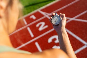 Over-the-shoulder view of a person holding a stopwatch at a running track- Stock Photo or Stock Video of rcfotostock | RC Photo Stock