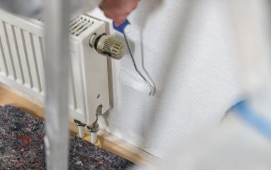 painter working with paint roller to paint behind a radiator the wall with white color. do it yourself concept image- Stock Photo or Stock Video of rcfotostock | RC Photo Stock