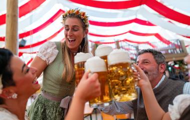 People celebrating Oktoberfest in a beer tent, raising mugs filled with beer for a toast, joyful smiles and festive atmosphere under the colorful tent : Stock Photo or Stock Video Download rcfotostock photos, images and assets rcfotostock | RC Photo Stock.: