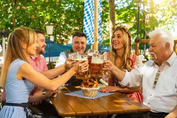 people in proper Tracht toasting and drinking in Bavarian beer garden at Oktoberfest, folk or beer festival in germany - Stock Photo or Stock Video of rcfotostock | RC Photo Stock