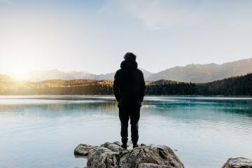 Person from behind looks at beautiful lake at sunrise.Relaxed, peaceful, thoughtful, happy and free at the mountain lake.- Stock Photo or Stock Video of rcfotostock | RC Photo Stock
