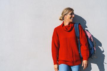 Portrait of a young woman with red sweater and backpack who looks to the right isolated on a concrete wall with copy space. Beautiful student girl looking sideways University concept image. : Stock Photo or Stock Video Download rcfotostock photos, images and assets rcfotostock | RC Photo Stock.: