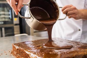 Pouring melted chocolate onto a cake layer in a bakery, creating a smooth chocolate coating in a professional baking environment : Stock Photo or Stock Video Download rcfotostock photos, images and assets rcfotostock | RC Photo Stock.: