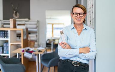 professional smiling tailor woman with hair Braid, wearing glasses and a blue striped shirt, stands in a modern workspace and holding a ruler.- Stock Photo or Stock Video of rcfotostock | RC Photo Stock