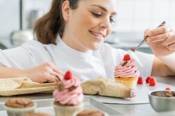 Professional women in pastry bakery as confectioner draped a piece of chocolate on a muffin topping with tweezers : Stock Photo or Stock Video Download rcfotostock photos, images and assets rcfotostock | RC Photo Stock.: