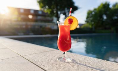 refreshing red cocktail garnished with a strawberry and orange slice by a poolside at sunset : Stock Photo or Stock Video Download rcfotostock photos, images and assets rcfotostock | RC Photo Stock.: