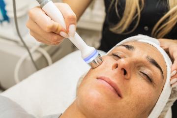 relaxed woman lying on the medical bed with her eyes closed while having hydrafacial clean procedure at a cosmetology salon.- Stock Photo or Stock Video of rcfotostock | RC Photo Stock