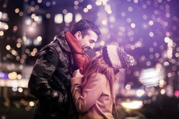 Romantic couple smiling warmly at each other in a winter cityscape, with festive lights and bokeh creating a magical atmosphere, both dressed in cozy winter coats, scarf, and knit hat : Stock Photo or Stock Video Download rcfotostock photos, images and assets rcfotostock | RC Photo Stock.: