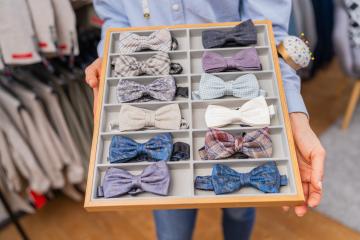 saleswoman holding a tray of various bow ties with a rack of suits in the background on a store- Stock Photo or Stock Video of rcfotostock | RC Photo Stock