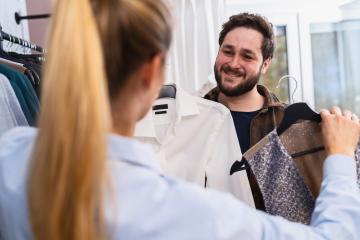 Saleswoman presenting a shirt to a male customer who is examining a patterned jacket at a store- Stock Photo or Stock Video of rcfotostock | RC Photo Stock