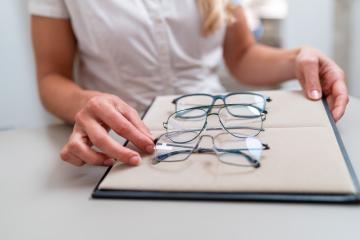 saleswomans hands adjusting eyeglasses on a display tray. focus on hands and glasses with blurred background. Optician Shop concept image.- Stock Photo or Stock Video of rcfotostock | RC Photo Stock