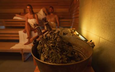 Sauna bucket with vihta (birch whisks), focus on foreground, people relaxing in the background at a finnish sauna. Wellness Spa Hotel Conept image.- Stock Photo or Stock Video of rcfotostock | RC Photo Stock