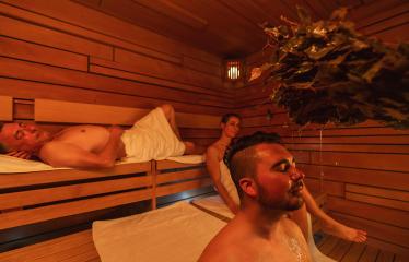 sauna session with a man enjoying a vihta treatment and others relaxing in the wooden room at a finnish sauna. Wellness Spa Hotel Conept image.- Stock Photo or Stock Video of rcfotostock | RC Photo Stock