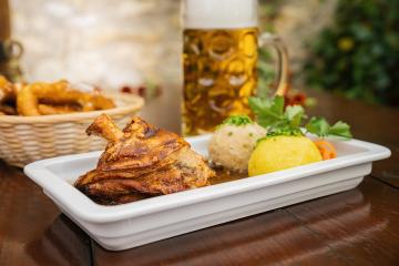 Schweinshaxe, in German cuisine, is a roasted ham hock (or pork knuckle). The ham hock is the end of the pig's leg, with potato dumpling, brezen and beer mug in a Bavarian beer garden or oktoberfest : Stock Photo or Stock Video Download rcfotostock photos, images and assets rcfotostock | RC Photo Stock.:
