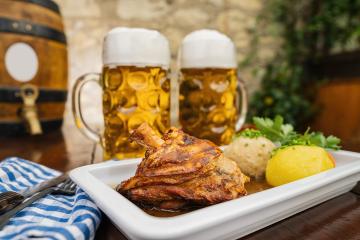 Schweinshaxe, traditional Bavarian cuisine with roasted ham hock (pork knuckle) with potato dumpling, brezen and tow beer glasses in a beer garden or oktoberfest : Stock Photo or Stock Video Download rcfotostock photos, images and assets rcfotostock | RC Photo Stock.: