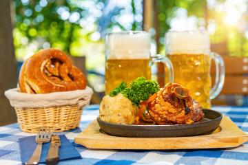 Schweinshaxe, traditional Bavarian cuisine with roasted ham hock (pork knuckle) with potato dumpling, brezen and beer mug on a table at beer garden or oktoberfest : Stock Photo or Stock Video Download rcfotostock photos, images and assets rcfotostock | RC Photo Stock.: