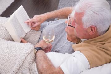 Senior couple enjoying a cozy moment together on a couch, reading a book while holding a glass of white wine, wrapped in soft blankets, symbolizing relaxation, love, and companionship in a warm settin : Stock Photo or Stock Video Download rcfotostock photos, images and assets rcfotostock | RC Photo Stock.: