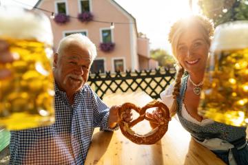 Senior man and young woman in Bavarian clothes holding beer mugs and pretzel, smiling at camera in a beer garden or Oktoberfest, Munich, Germany : Stock Photo or Stock Video Download rcfotostock photos, images and assets rcfotostock | RC Photo Stock.: