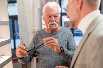 Senior man trying on new glasses and talks about it with an optician in store- Stock Photo or Stock Video of rcfotostock | RC Photo Stock