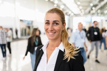 smiling businesswoman at a trade fair holding tablet- Stock Photo or Stock Video of rcfotostock | RC Photo Stock