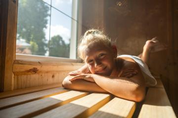 Smiling child lying on a sauna bench, sunlight streaming in from a window- Stock Photo or Stock Video of rcfotostock | RC Photo Stock