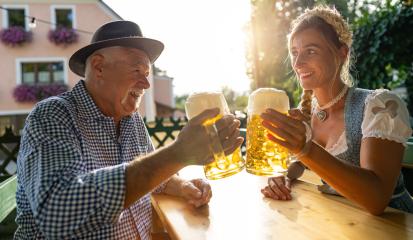 Smiling elderly man and young woman toasting beer mugs, traditional Bavarian outfits in beer garden or oktoberfest at Bavaria, Germany- Stock Photo or Stock Video of rcfotostock | RC Photo Stock
