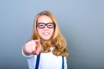 Smiling girl with glasses pointing at the camera against a simple blue background : Stock Photo or Stock Video Download rcfotostock photos, images and assets rcfotostock | RC Photo Stock.: