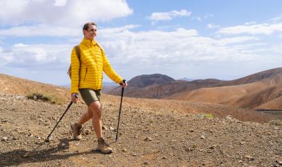 Smiling hiker in yellow jacket with trekking poles in mountainous desert terrain : Stock Photo or Stock Video Download rcfotostock photos, images and assets rcfotostock | RC Photo Stock.: