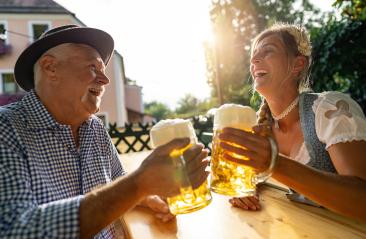 Smiling man and young woman toasting beer mugs, traditional Bavarian outfits in beer garden or oktoberfest at Bavaria, Germany- Stock Photo or Stock Video of rcfotostock | RC Photo Stock
