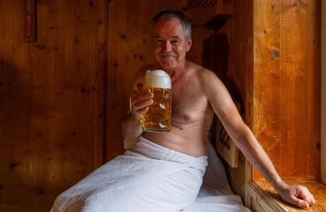 Smiling man in sauna holding german beer mug, towel wrapped around waist. Spa Wellness concept image- Stock Photo or Stock Video of rcfotostock | RC Photo Stock