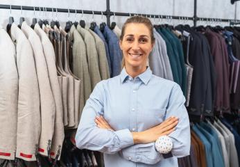 Smiling tailor with crossed arms in front of a rack of suits in a clothing store : Stock Photo or Stock Video Download rcfotostock photos, images and assets rcfotostock | RC Photo Stock.: