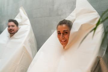 Smiling woman and man wrapped in thermal hot steam sauna bags in a spa hotel, steam and plants around : Stock Photo or Stock Video Download rcfotostock photos, images and assets rcfotostock | RC Photo Stock.: