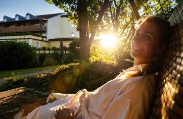 Smiling woman enjoying the morning sun on a wicker swing in a garden at sap wellness resort hotel- Stock Photo or Stock Video of rcfotostock | RC Photo Stock