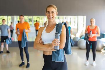Smiling woman holding water bottle with fitness class members in the background : Stock Photo or Stock Video Download rcfotostock photos, images and assets rcfotostock | RC Photo Stock.: