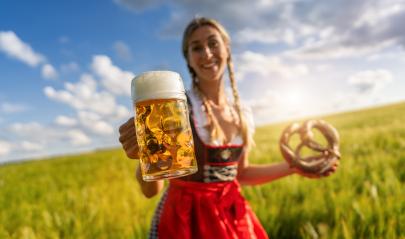 Smiling woman in Bavarian tracht offering beer and pretzel in a sunny  wheat field celebrating Oktoberfest festival in munich.- Stock Photo or Stock Video of rcfotostock | RC Photo Stock