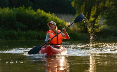 Smiling woman paddling a kayak on a serene river during golden hour. Kayak Water Sports concept image- Stock Photo or Stock Video of rcfotostock | RC Photo Stock
