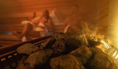 Steam rising from sauna stones with blurred people in the background, warm glowing light. relaxing in finnish sauna spa hotel concept image- Stock Photo or Stock Video of rcfotostock | RC Photo Stock