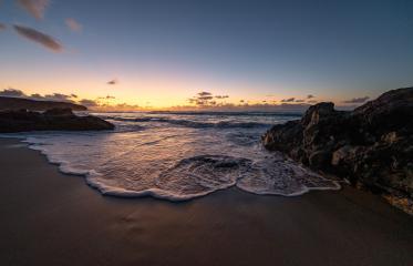 Sunset view at the beach with waves gently crashing against rocks under a colorful sky- Stock Photo or Stock Video of rcfotostock | RC Photo Stock