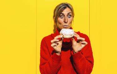 Surprised woman with red sweater bite into a strawberry jam filled berliner doughnut against yellow wall : Stock Photo or Stock Video Download rcfotostock photos, images and assets rcfotostock | RC Photo Stock.: