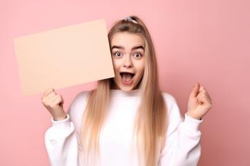 Surprised young woman holding beige blank sign, pink background- Stock Photo or Stock Video of rcfotostock | RC Photo Stock