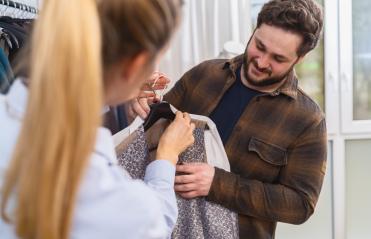 Tailor and customer looking at a wedding suit, customer holding hanger and touching fabric at a store- Stock Photo or Stock Video of rcfotostock | RC Photo Stock