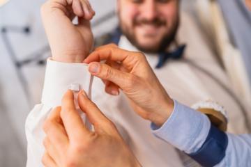 Tailor assists man with cufflinks, both hands visible, man smiles in background at a weddomg store : Stock Photo or Stock Video Download rcfotostock photos, images and assets rcfotostock | RC Photo Stock.: