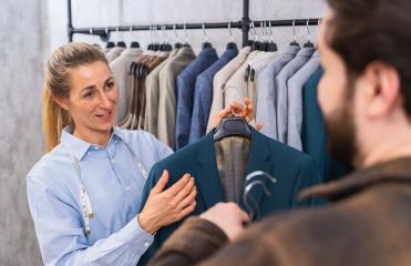 Tailor holding a teal jacket for a male client, both engaging in conversation at a store : Stock Photo or Stock Video Download rcfotostock photos, images and assets rcfotostock | RC Photo Stock.: