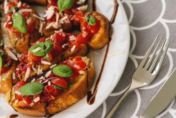 Tasty savory tomato Italian appetizers, or bruschetta, on slices of toasted baguette garnished with basil, on a Plate- Stock Photo or Stock Video of rcfotostock | RC-Photo-Stock